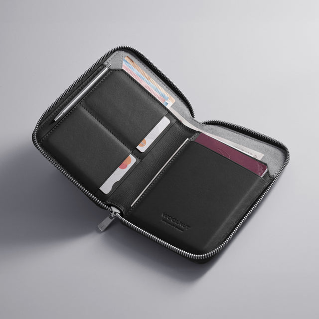 WOOLNUT Black Leather travel folio with zip closure, featuring organized storage for passports, boarding passes, cards, cash, travel documents, and a mini pen